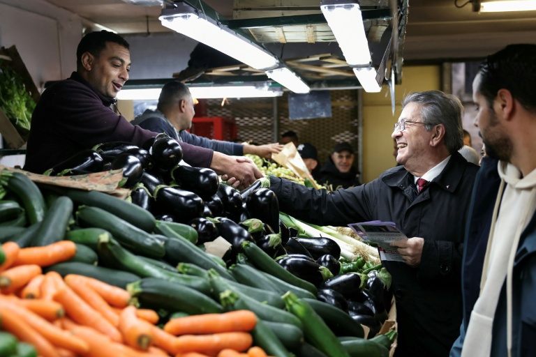 Jean-Luc Mélenchon (c), leader de La France Insoumise (LFI), salue un vendeur lors d'une visite au marché de Choisy-le-Roi, le 2 novembre 2025 dans le Val-de-Marne