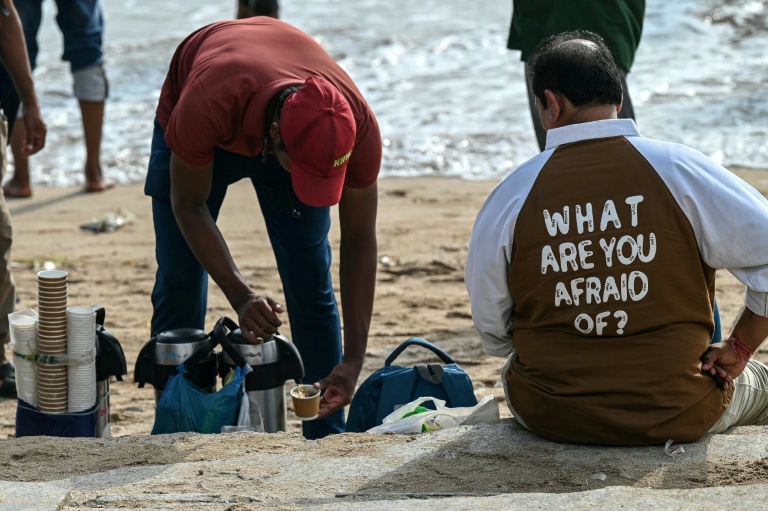 Un vendeur de thé prépare une tasse pour un client sur la plage de Juhu, à Bombay, le 6 août 2026 en Inde
