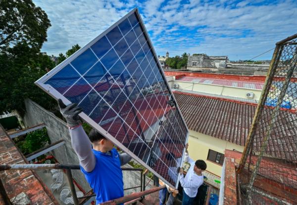 Une équipe de techniciens de systèmes photovoltaïques hisse des panneaux sur le toit d'une cantine pour personnes âgées géré par l’Eglise catholique, dans le quartier de Guanabacoa à La Havane, le 4 février 2026