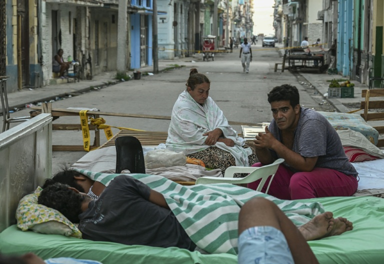 Plusieurs familles passent la nuit sur des lits installés dans la rue, dans un quartier central de La Havane, le 30 juillet 2026, après l'effondrement partiel de leur immeuble