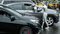 L'artiste de rue Ari Munandar (d), le corps recouvert de peinture argentée, fait la manche sous la pluie à un carrefour de Jakarta, le 1er avril 2025 en Indonésie