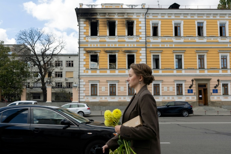 Une femme marche le 5 octobre 2026 devant le bâtiment de l'Académie nationale des sciences à Kiev endommagé par une frappe russe