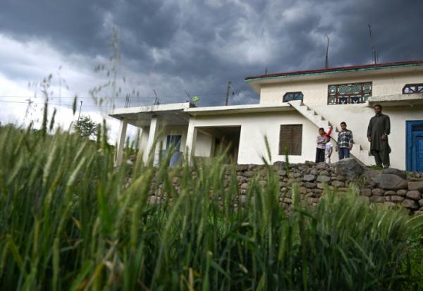 Mohammad Rashid (d) devant sa maison, surmontée d'un bunker récemment construit, dans le village de Kasaliyan, près de la frontière avec le Pakistan, le 6 avril 2026 en Inde