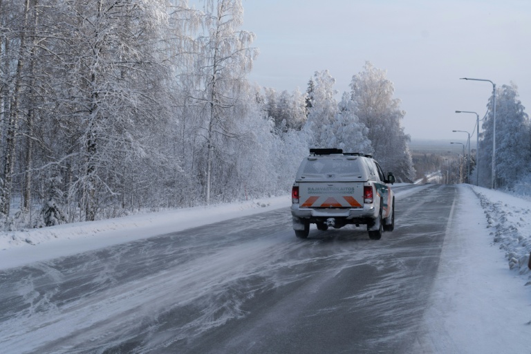 Un véhicule des garde-frontières finlandais roule sur la route déserte vers la frontière russe