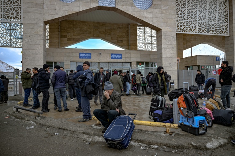 Des Iraniens attendent des bus après avoir franchi le principal poste-frontière de Razi-Kapiköy entre l'Iran et la Turquie, le 31 janvier 2026
