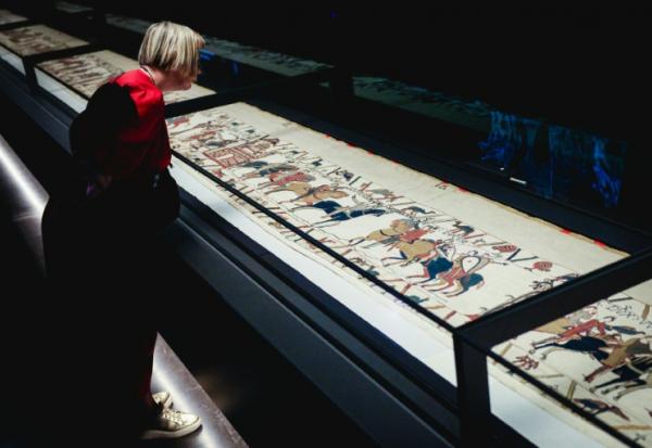 Une femme se penche pour observer la Tapisserie de Bayeux lors d'une avant-première réservée à la presse, organisée en amont de l'inauguration officielle au British Museum, dans le centre de Londres, le 7 septembre 2026