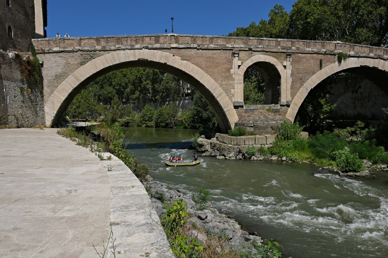 Des personnes naviguent en canot pneumatique sur le Tibre, passant devant l'île Tibérine, sur un tronçon du fleuve situé entièrement dans la zone urbaine du centre de Rome, le 14 août 2026