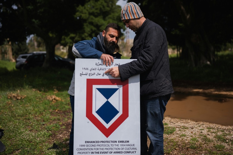 Des employés installent un panneau de l'Unesco sur le site de l'hippodrome romain de Tyr, dans le sud du Liban, le 23 mars 2026