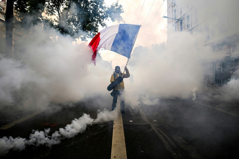 Un manifestant agite un drapeau français au milieu des gaz lacrymogènes lors d'une nouvelle manifestation contre la vie chère, le 31 octobre 2026 à Lyon