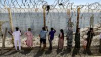 Des personnes attendent derrière une clôture surmontée de barbelés le retour de proches ayant tenté de franchir la frontière pour entrer dans l’enclave espagnole de Ceuta, le 2 août 2026 à Fnideq