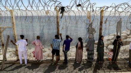 Des personnes attendent derrière une clôture surmontée de barbelés le retour de proches ayant tenté de franchir la frontière pour entrer dans l’enclave espagnole de Ceuta, le 2 août 2026 à Fnideq