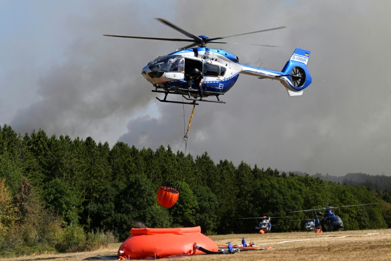 Des hélicoptères de la police chargent de l'eau pour lutter contre un incendie de forêt à Hurtgenwald, dans l'ouest de l'Allemagne, le 14 août 2026