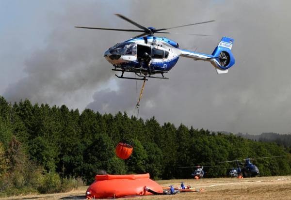 Des hélicoptères de la police chargent de l'eau pour lutter contre un incendie de forêt à Hurtgenwald, dans l'ouest de l'Allemagne, le 14 août 2026