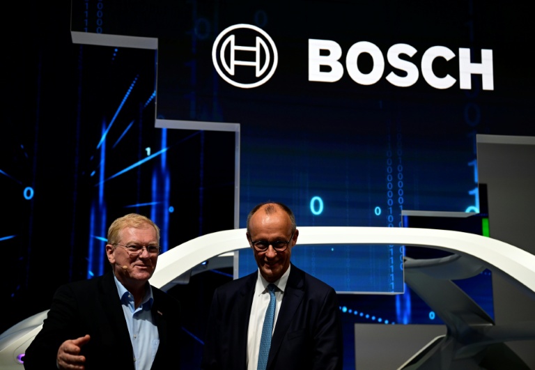 Le PDG de Bosch, Stefan Hartung (g) et le chancelier allemand lors de l'ouverture du Salon international de l'automobile IAA à Munich, le 9 septembre 2025 dans le sud de l'Allemagne