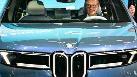 Le chancelier allemand Friedrich Merz assis dans une BMW IX3 sur le stand du constructeur automobile lors de l'ouverture du Salon international de l'automobile IAA, le 9 septembre 2025 à Munich, dans le sud de l'Allemagne