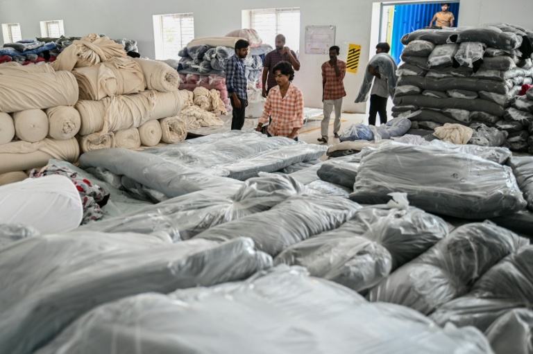 Des ouvriers stockent des tissus utilisés pour fabriquer des t-shirts dans une usine de confection à Tiruppur, dans l'État du Tamil Nadu, dans le sud de l'Inde, le 24 septembre 2025
