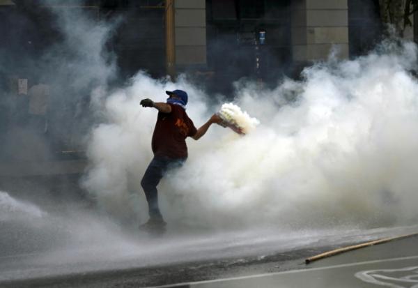 Un manifestant renvoie une grenade lacrymogène tirée par la police lors d'une manifestation devant le bâtiment du Parlement, où la réforme du travail du président argentin Javier Milei est examinée, à Buenos Aires, le 19 février 2026