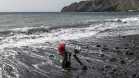 Vania Tavares ramasse du sable noir sur une plage dégradée par l'exploitation commerciale, près de Ribeira da Barca, le 20 mai 2026 au Cap-Vert 