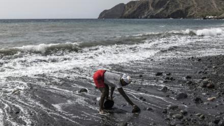 Vania Tavares ramasse du sable noir sur une plage dégradée par l'exploitation commerciale, près de Ribeira da Barca, le 20 mai 2026 au Cap-Vert 