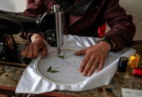 La couturière Rahima Alavi brode à la machine à coudre un tissu dans sa boutique à Bamiyan, le 26 janvier 2026 en Afghanistan