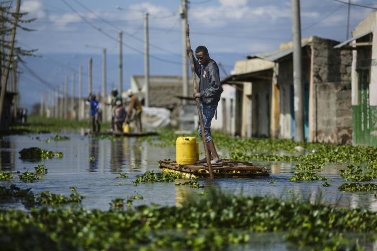 Des habitants se déplacent le 17 novembre 2025 à l'aide de radeaux de fortune dans une rue de ce qui fut leur quartier des rives du lac Naivasha, dans le centre du Kenya, inondé par la montée des eaux