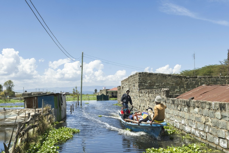 Un bateau transporte un homme contraint par la montée des eaux d'évacuer avec ses biens son quartier des bords du lac Naivasha, dans le centre du Kenya, le 17 novembre 2025
