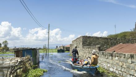 Un bateau transporte un homme contraint par la montée des eaux d'évacuer avec ses biens son quartier des bords du lac Naivasha, dans le centre du Kenya, le 17 novembre 2025