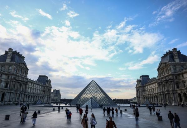 Des touristes près de la pyramide du Louvre, conçue par l'architecte sino-américain Ieoh Ming Pei, le 28 février 2025