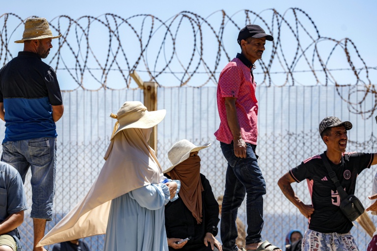 Des personnes attendent derrière une clôture surmontée de barbelés le retour de proches ayant tenté de franchir la frontière pour entrer dans l’enclave espagnole de Ceuta, le 2 août 2026 à Fnideq
