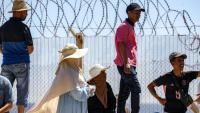 Des personnes attendent derrière une clôture surmontée de barbelés le retour de proches ayant tenté de franchir la frontière pour entrer dans l’enclave espagnole de Ceuta, le 2 août 2026 à Fnideq