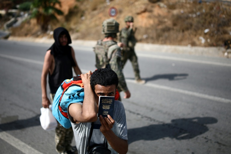 Un candidat à l'émigration montre son passeport yéménite alors qu'il est raccompagné par des militaires jusqu'au poste-frontière entre le Maroc et l'enclave espagnole de Ceuta, le 2 août 2026 
