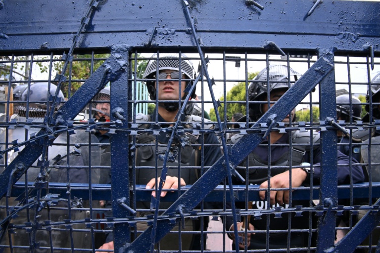 Des policiers montent la garde lors d'une manifestation de partisans de l'ancien Premier ministre népalais KP Sharma Oli protestant contre son arrestation, le 29 mars 2026 à Katmandou, au Népal