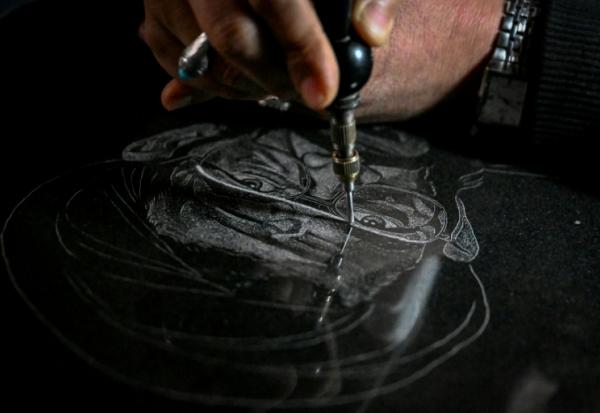 L'artiste Sadiq Poya grave le portrait d'une personne décédée sur une pierre tombale à Quetta, au Pakistan, le 17 février 2026