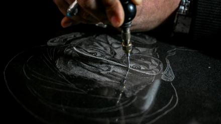 L'artiste Sadiq Poya grave le portrait d'une personne décédée sur une pierre tombale à Quetta, au Pakistan, le 17 février 2026