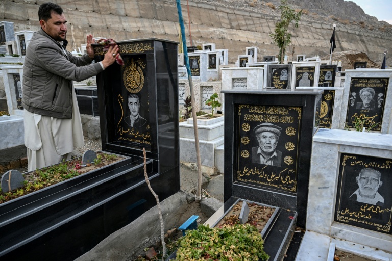 Talib Hussain nettoie la pierre tombale sur laquelle est gravé le portrait de son père décédé, dans un cimetière de Quetta, au Pakistan, le 17 février 2026