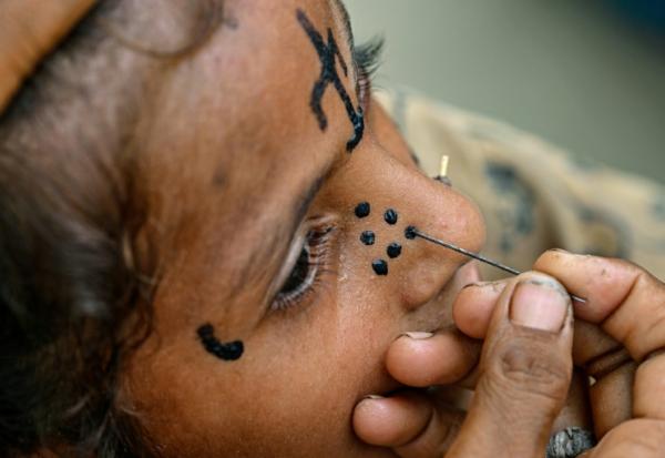 Un tatouage traditionnel est dessiné sur le visage de la jeune Champa, 7 ans, à la colonie Jogi à Umerkot, un district à majorité hindoue, le 14 juillet 2025 au Pakistan