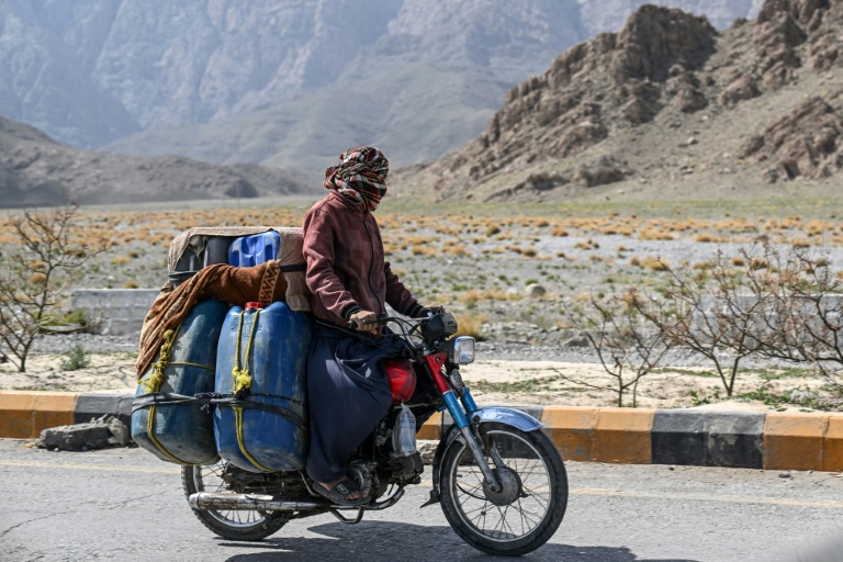 Un vendeur de carburant transporte sur sa moto des jerricans d'essence iranienne de contrebande, à la périphérie de Quetta, dans la province du Baloutchistan, au Pakistan, le 14 mars 2026