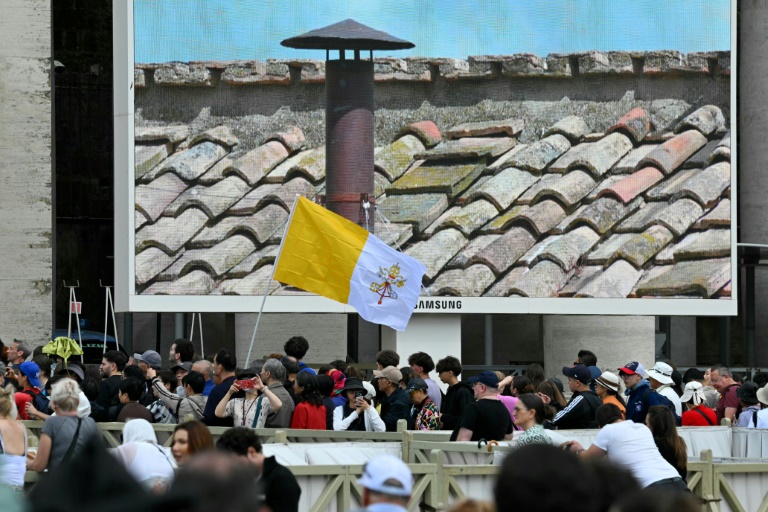 Des fidèles à Rome scrutent sur un écran la cheminée de la chapelle Sixtine au deuxième jour du conclave le 8 mai 2025
