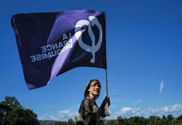 Une sympathisante de La France insoumise (LFI) tient un drapeau lors des universités d'été du parti (LFI), le 22 août 2026 à  Châteauneuf-sur-Isère, dans la Drôme 