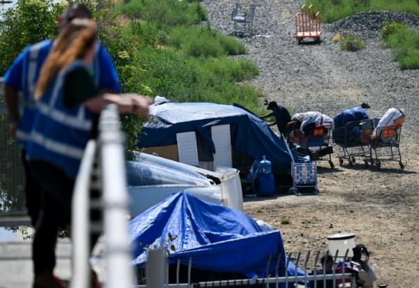 Des employés d'une association d'aide aux sans-abris veillent sur un campement de SDF, à Los Angeles, le 1er juin 2026