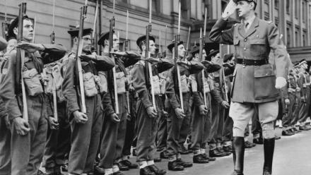 Le chef des Forces françaises libres (FFL), Charles de Gaulle, salue des marins alors qu'il passe en revue les troupes françaises lors du défilé militaire célébrant la fête nationale française à Londres, le 14 juillet 1942, durant la Seconde Guerre mondiale