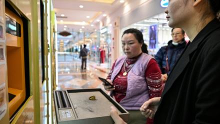 Une employée aide une cliente à vendre un bijou en or dans un automate de Shanghai, en Chine, le 29 janvier 2026