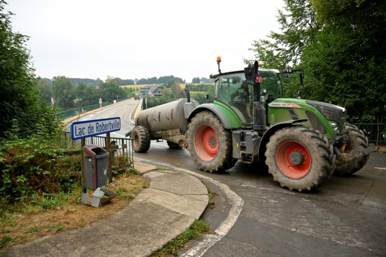 Un agriculteur conduit un tracteur équipé d'une citerne d'eau sur le barrage du lac de Robertville, à Waimes, alors qu'un incendie fait rage dans la réserve naturelle des Hautes Fagnes ,le 17 août 2026 en Belgique