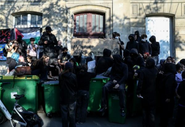Des manifestants se tiennent debout sur des poubelles empilées à l'entrée du lycée Arago à Paris, le 29 septembre 2026