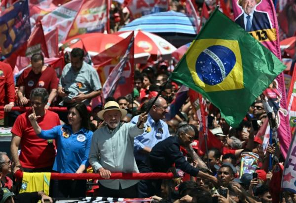 Le président brésilien de gauche Luiz Inacio Lula da Silva (C) agite le drapeau national lors d'un meeting de campagne à la veille du premier tour de la présidentielle, le 3 octobre 2026 à Sao Paulo