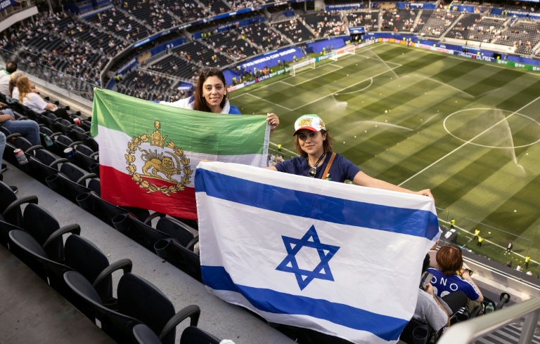 Des spectatrices assistant au match entre l'Iran et la Nouvelle-Zélande, brandissent un drapeau utilisé par l'Iran avant la révolution islamique, et un drapeau israélien, à l'intérieur du SoFi Stadium à Inglewood, près de Los Angeles, le 15 juin 2026