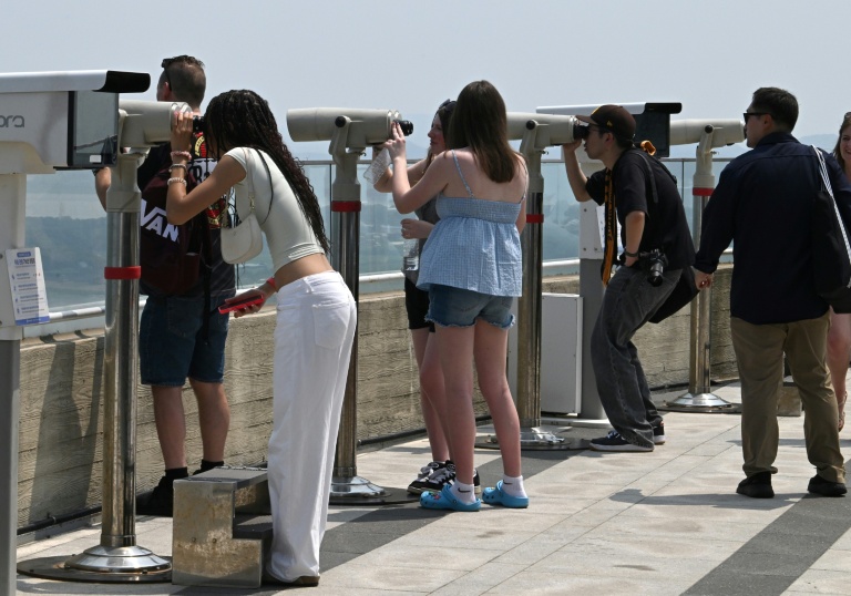 Des touristes utilisent des jumelles pour observer le territoire nord-coréen depuis une plate-forme d'observation sud-coréenne située à l'Écoparc de la Paix d'Aegibong, à Gimpo, le 1er juillet 2026 