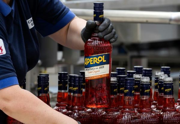 Un ouvrier de l'usine phare du groupe Campari à Novi Ligure, dans le nord-ouest de l'Italie, tient une bouteille d'Aperol, le 21 juillet 2026