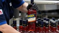 Un ouvrier de l'usine phare du groupe Campari à Novi Ligure, dans le nord-ouest de l'Italie, tient une bouteille d'Aperol, le 21 juillet 2026