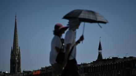 Des passants se protègent de la chaleur avec un parapluie, le 6 juillet 2026 à Bordeaux 